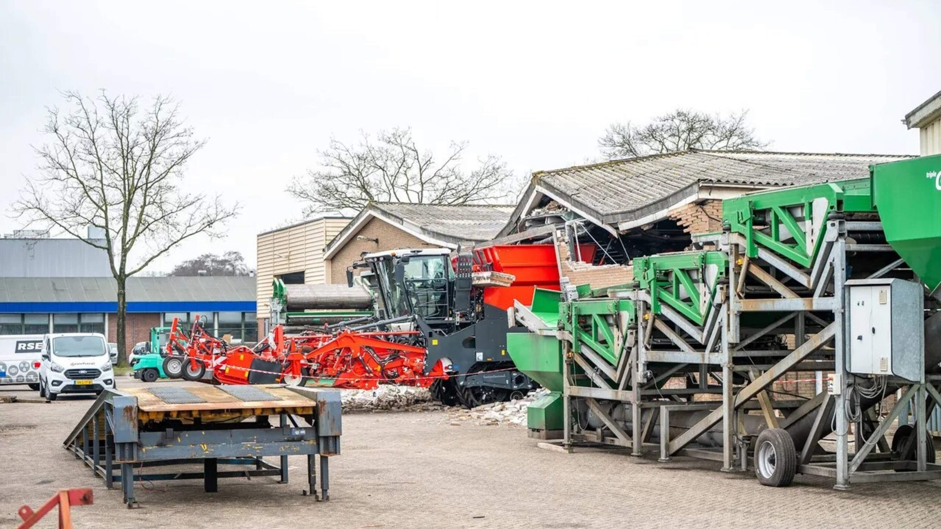 Rooimachine botst tegen bedrijfspand in Oosterwolde, flinke schade